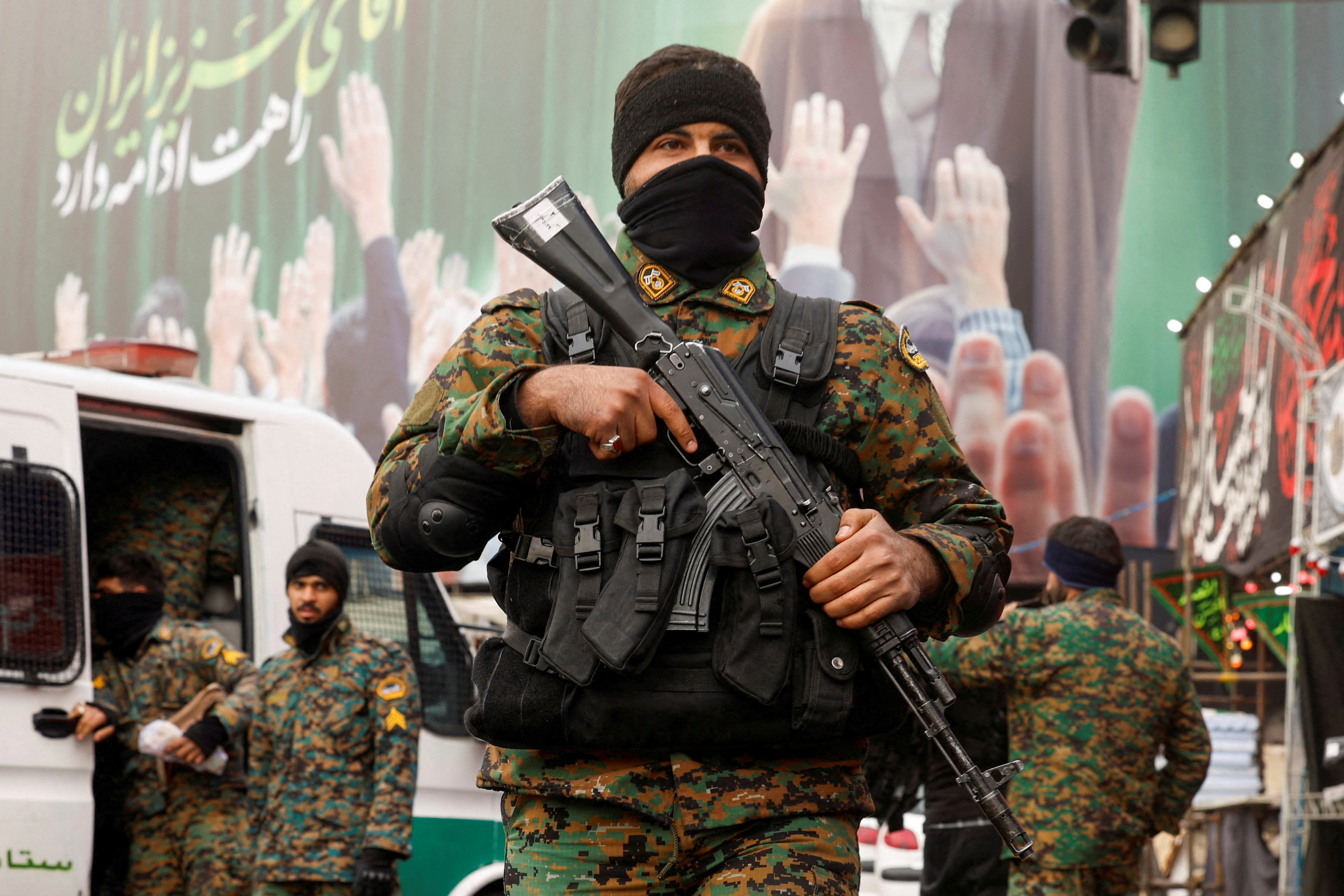Members of the police stand guard on a street, with a large billboard featuring Iran's late Supreme Leader Ayatollah Ali Khamenei in the background, in Tehran
