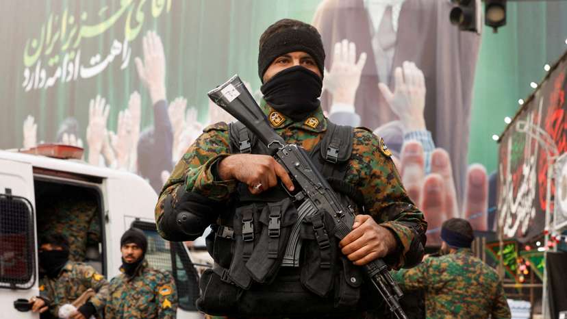 Members of the police stand guard on a street, with a large billboard featuring Iran's late Supreme Leader Ayatollah Ali Khamenei in the background, in Tehran