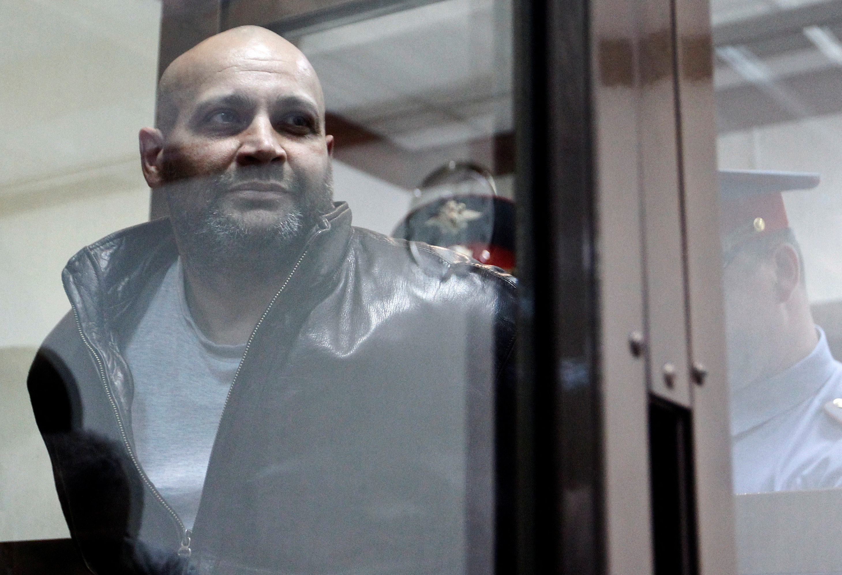 FILE PHOTO: Khadzhikurbanov is escorted into a glass-walled cage before a court hearing in Moscow