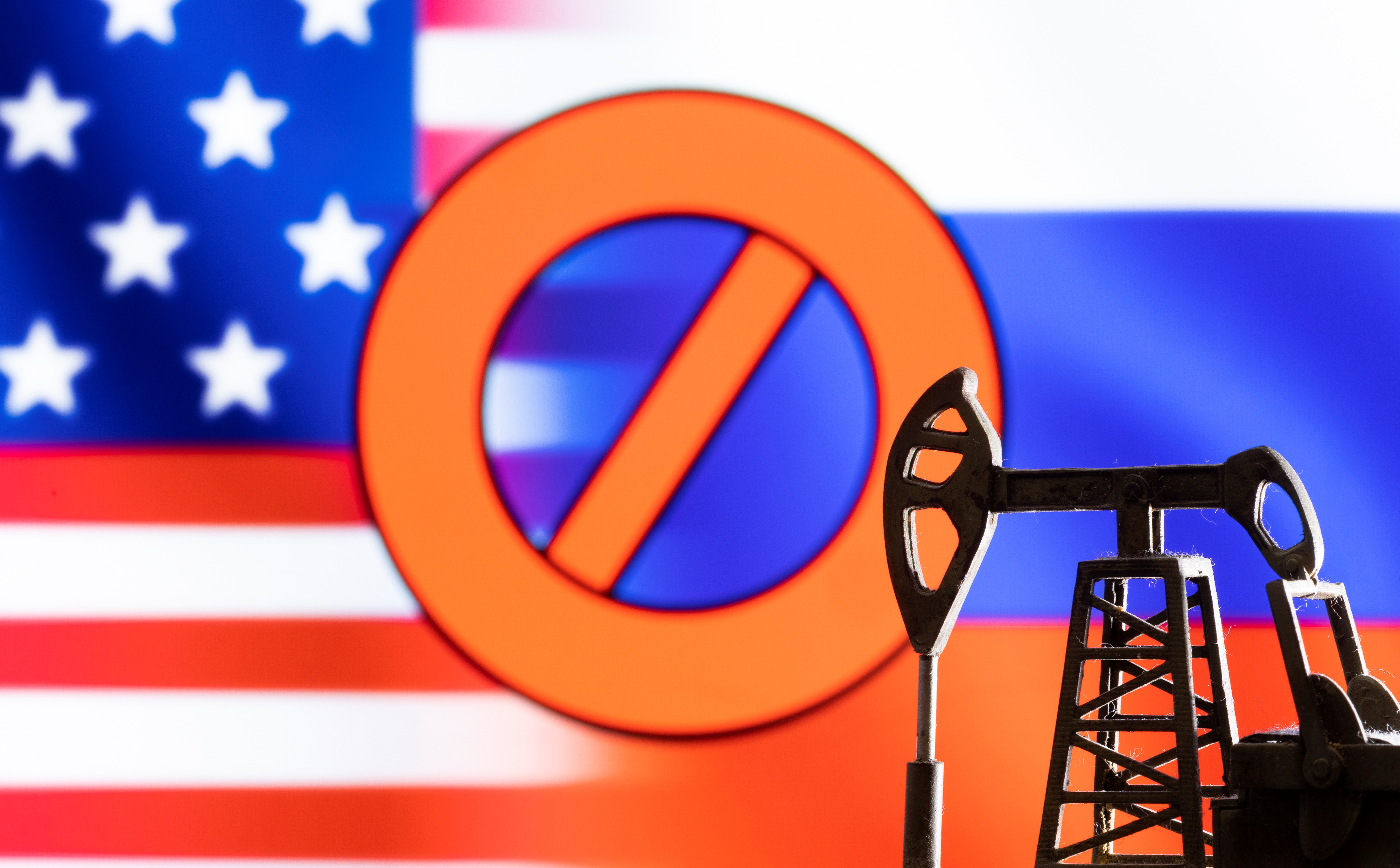 Illustration shows pump jack in front sign "stop",  U.S. and Russia flag colours