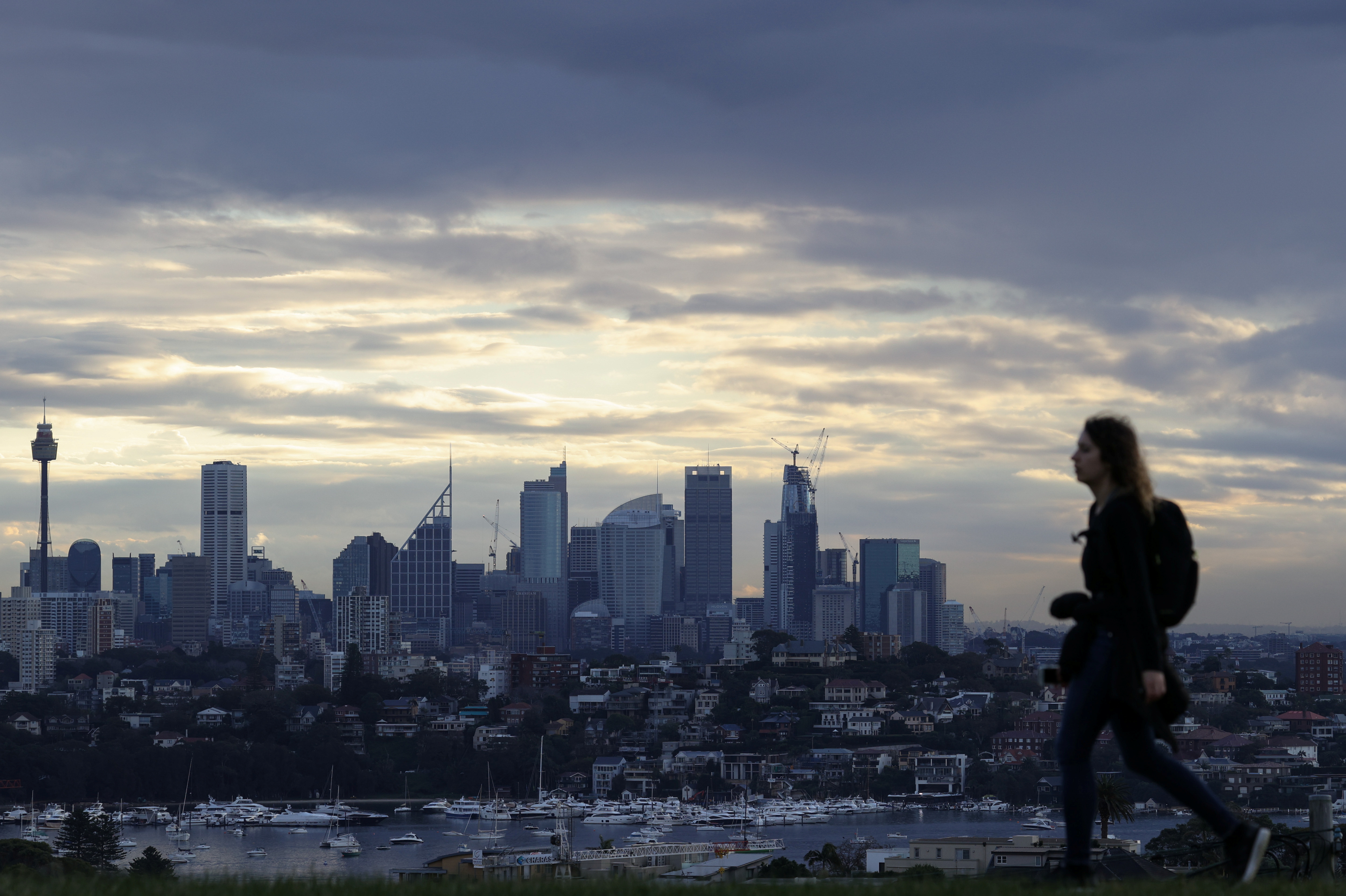 A woman walks on a hill overlooking the city centre skyline in Sydney