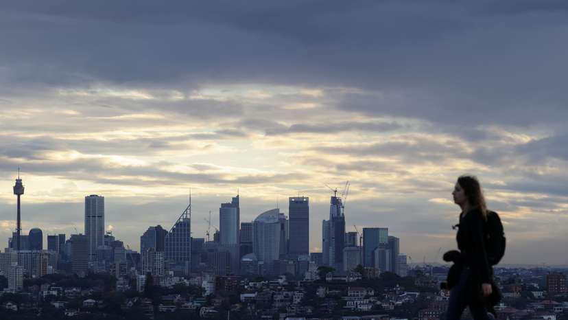 A woman walks on a hill overlooking the city centre skyline in Sydney