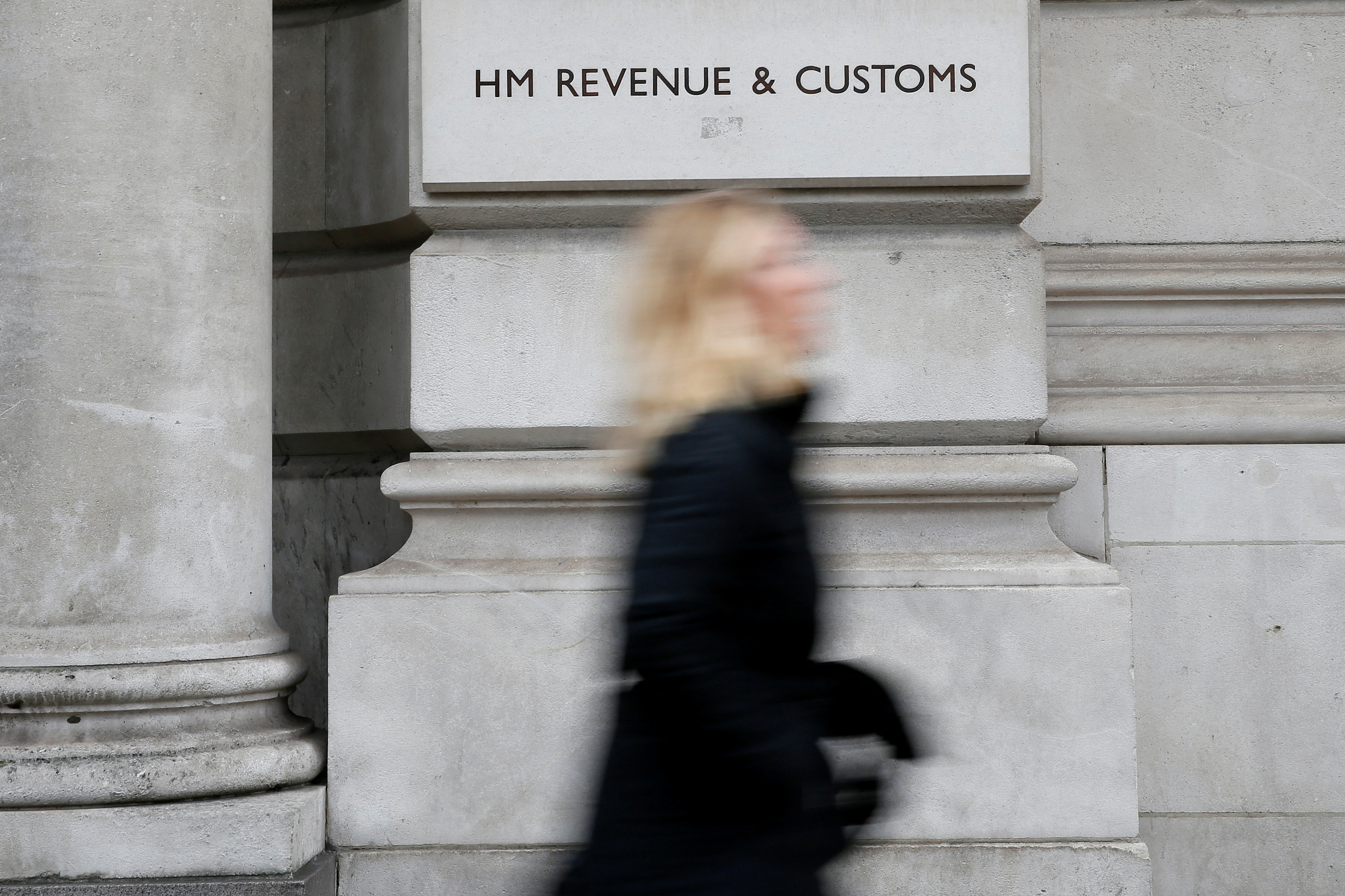 FILE PHOTO: A pedestrian walks past the headquarters of Her Majesty's Revenue and Customs (HMRC) in central London