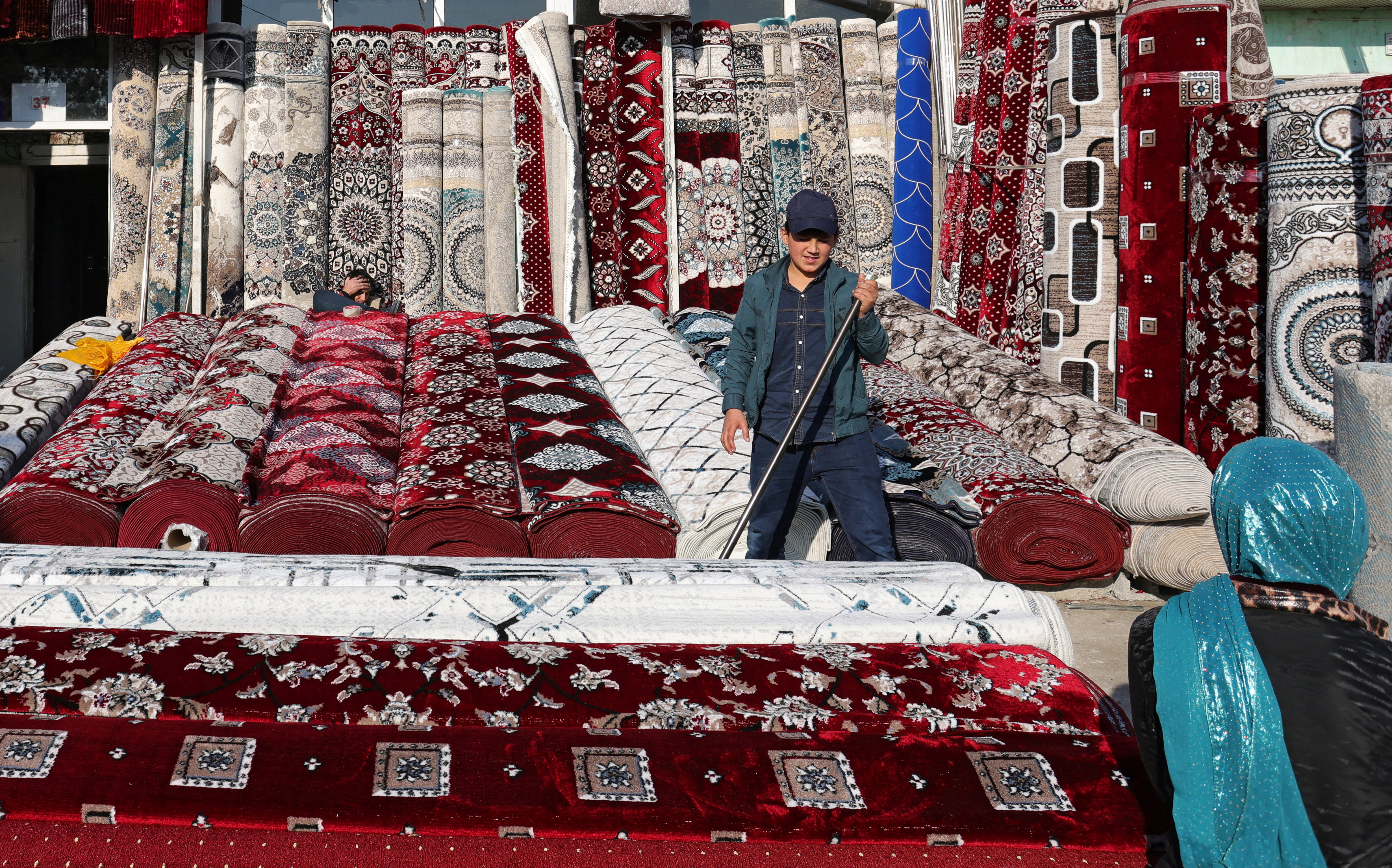 A vendor sells carpets at a local market in Hulbuk