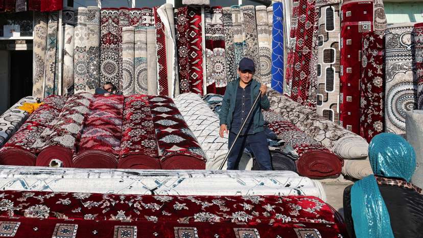 A vendor sells carpets at a local market in Hulbuk