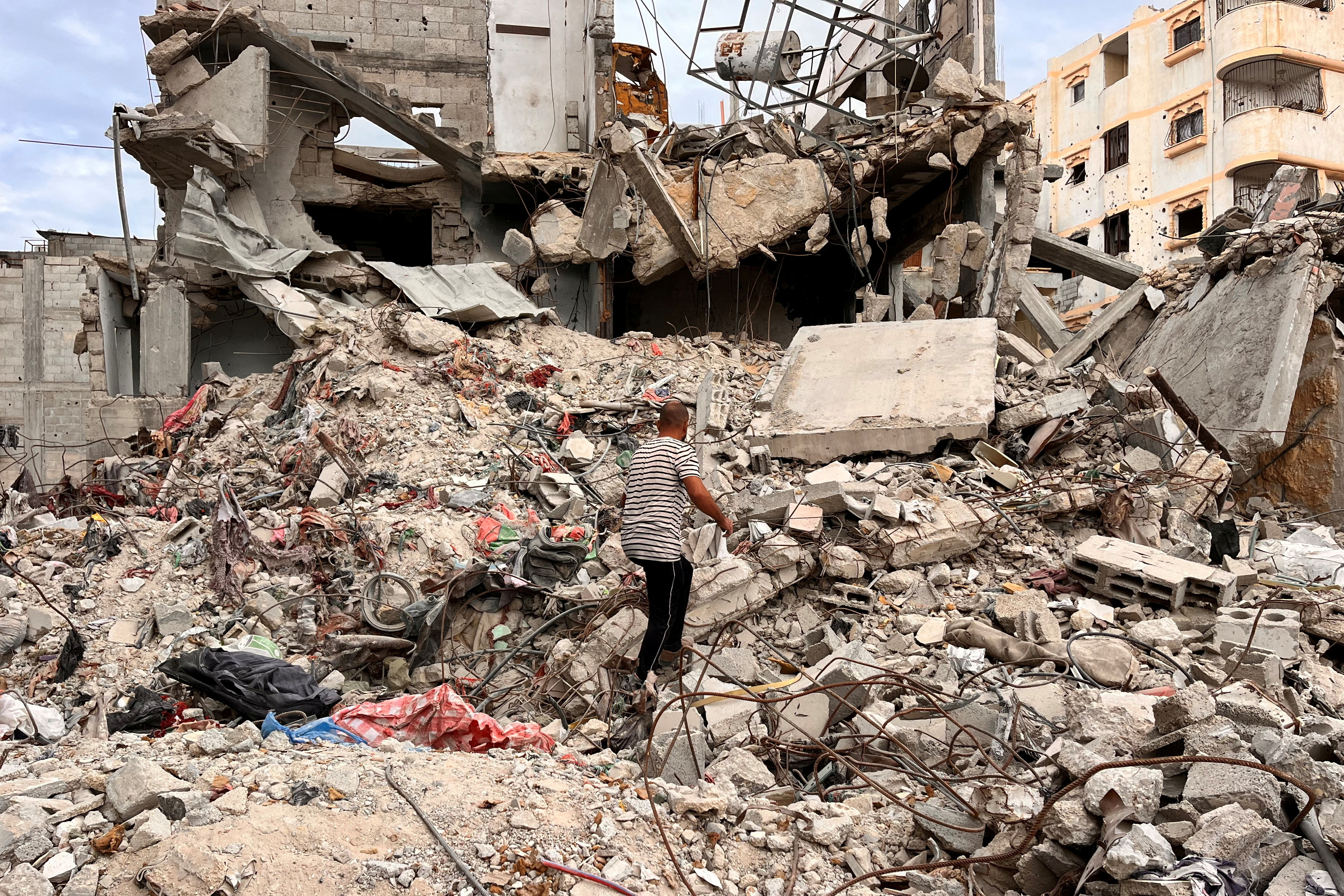 Palestinian man Moein Abu Odeh searches for clothes through the rubble of a house destroyed in the Israeli military offensive, in Khan Younis in the southern Gaza Strip
