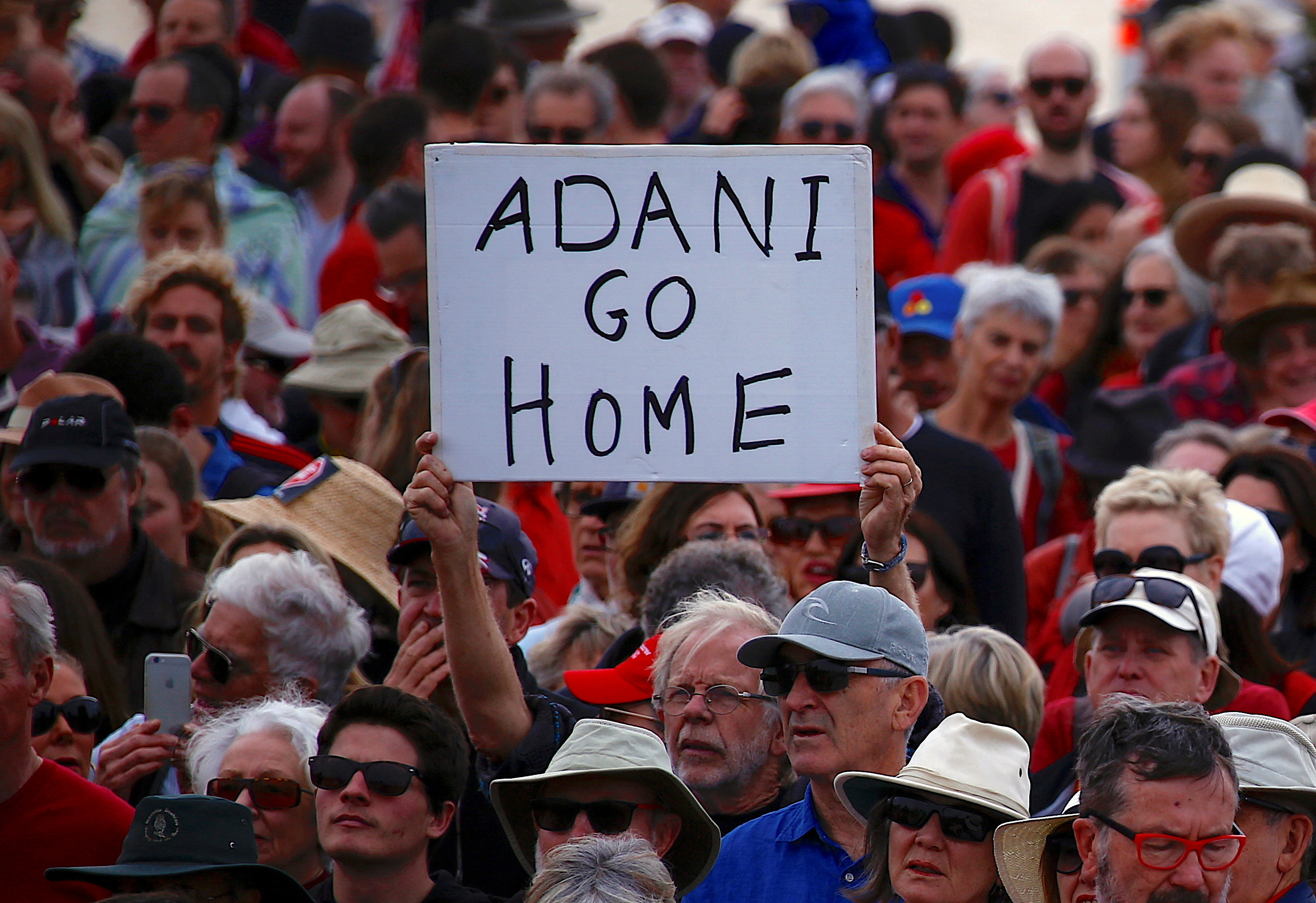 FILE PHOTO: A protester holds a sign as he participates in a national Day of Action against the Indian mining company Adani's planned coal mine project in north-east Australia, at Sydney's Bondi Beach in Australia