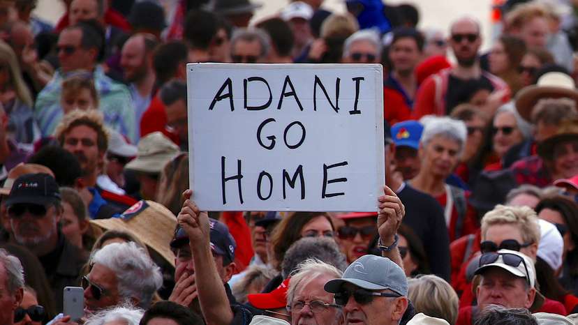 FILE PHOTO: A protester holds a sign as he participates in a national Day of Action against the Indian mining company Adani's planned coal mine project in north-east Australia, at Sydney's Bondi Beach in Australia