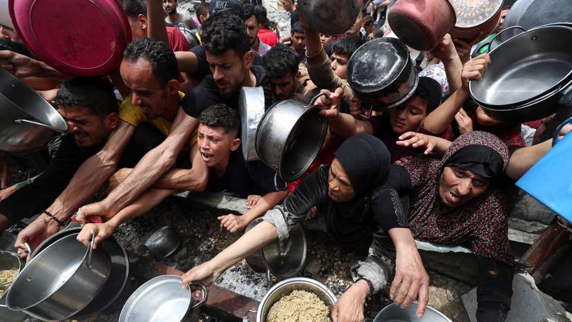 Palestinians wait to receive food cooked by a charity kitchen, in Jabalia