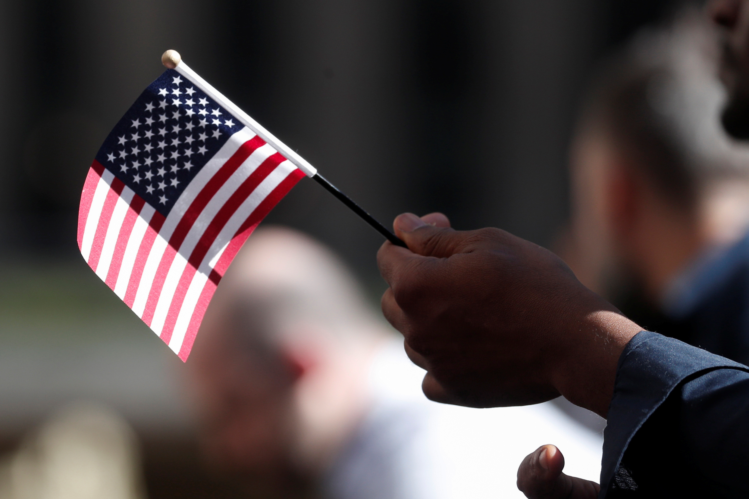 A citizenship candidate holds a flag during the U.S. Citizenship and Immigration Services (USCIS) naturalization ceremony at Rockefeller Plaza in New York City