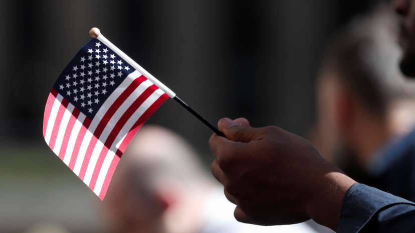 A citizenship candidate holds a flag during the U.S. Citizenship and Immigration Services (USCIS) naturalization ceremony at Rockefeller Plaza in New York City