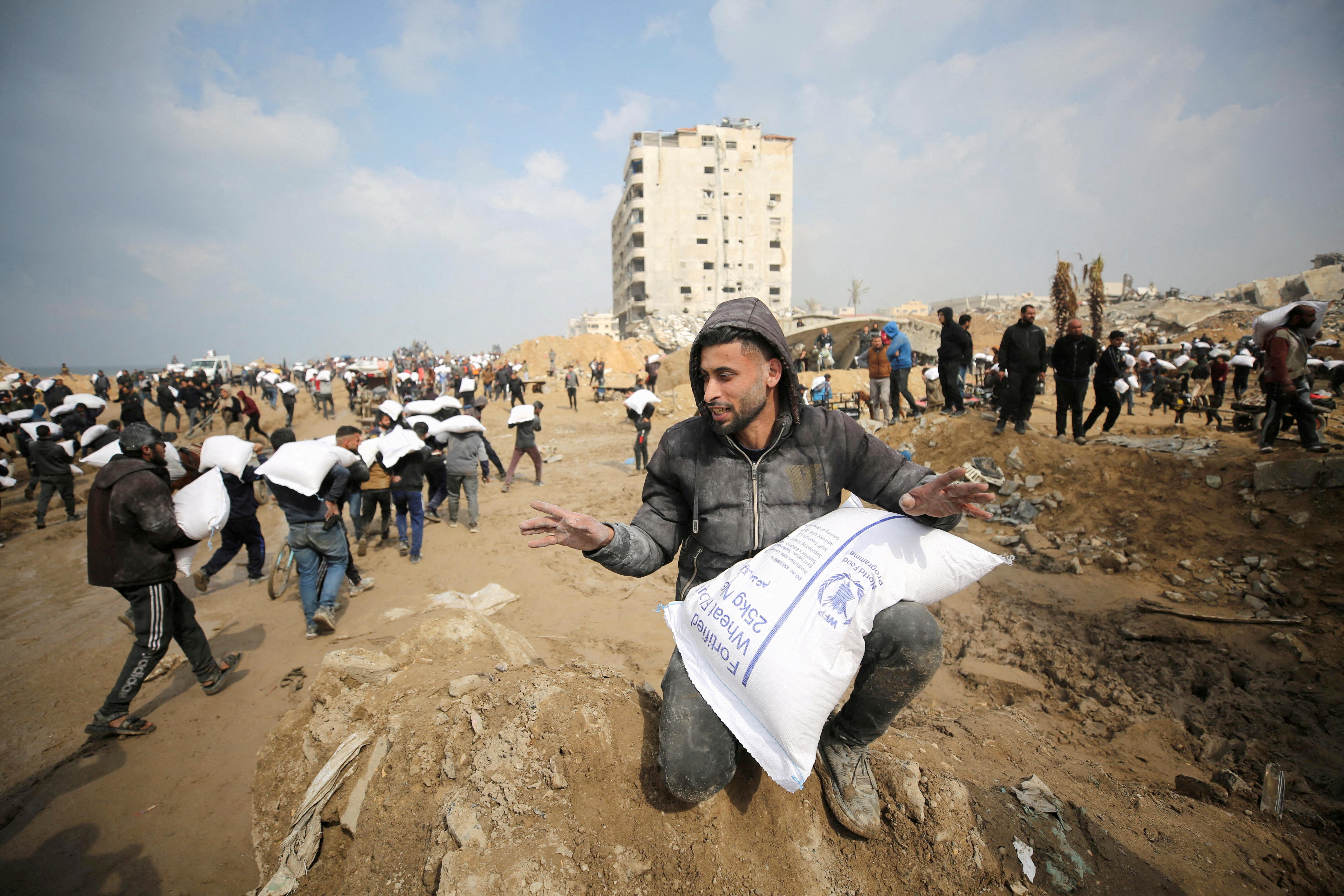 FILE PHOTO: Palestinians carry bags of flour they grabbed from an aid truck near an Israeli checkpoint in Gaza City
