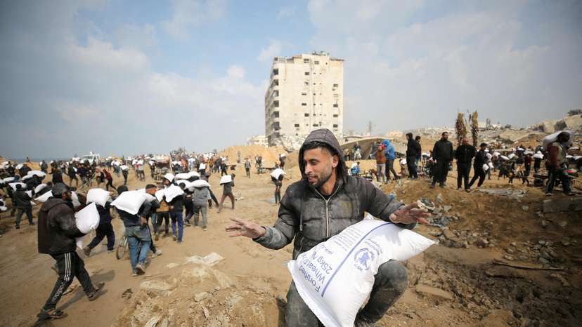 FILE PHOTO: Palestinians carry bags of flour they grabbed from an aid truck near an Israeli checkpoint in Gaza City