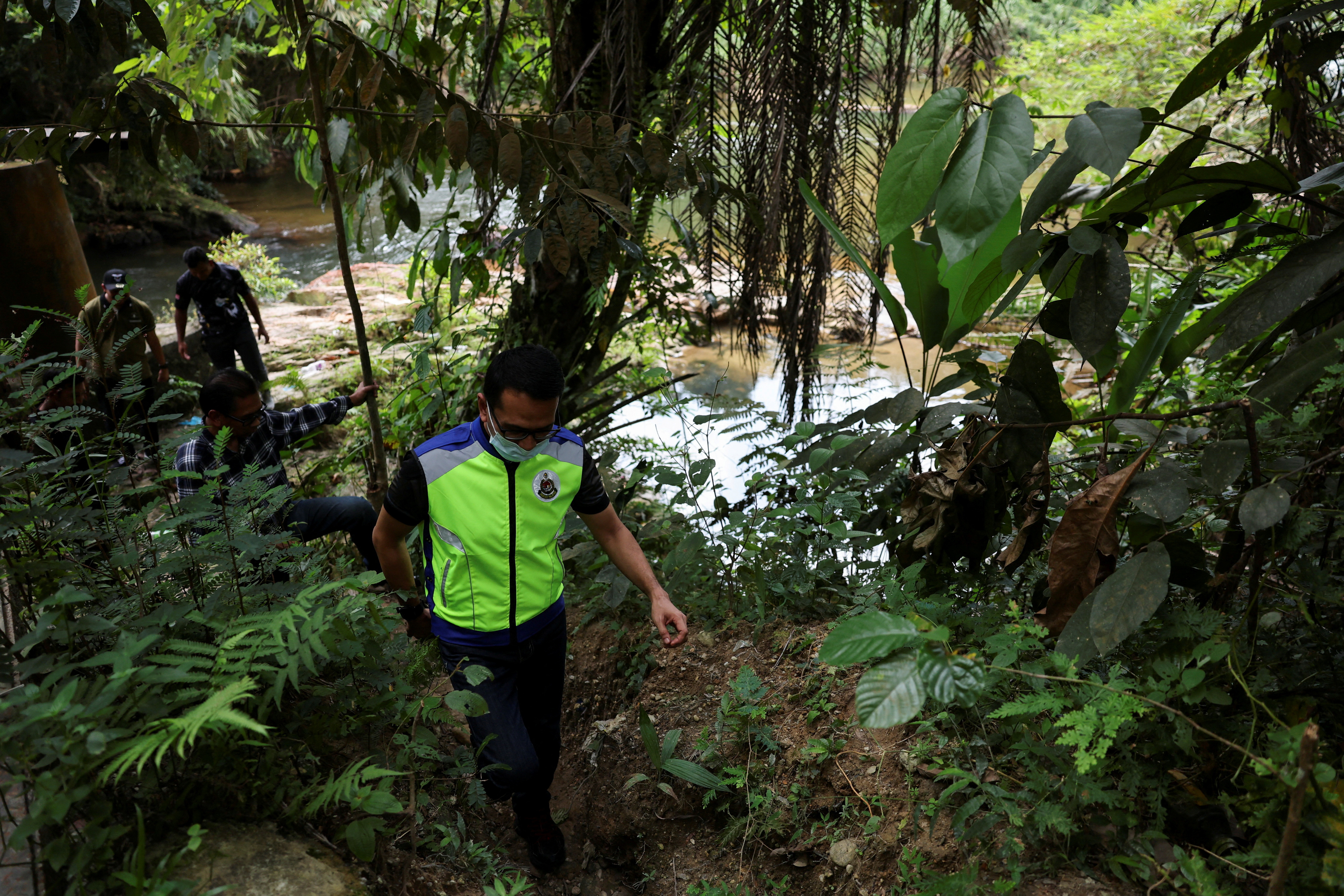 FILE PHOTO: Immigration officers check a riverine area near an immigration detention centre where more than 100 Myanmar migrants, including Rohingya refugees, escaped, at Bidor