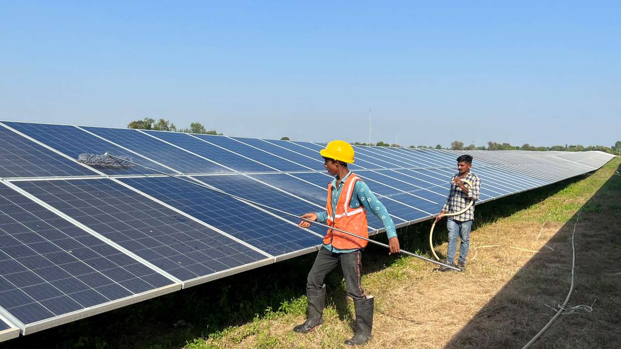 FILE PHOTO: Workers clean panels at a solar park in Modhera