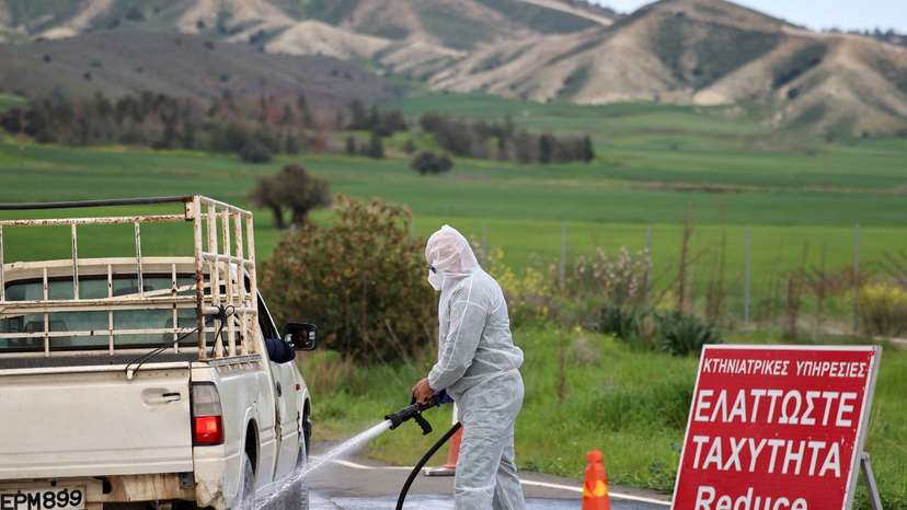 Man in a hazmat suit disinfects a vehicle and the road leading to farming units Oroklini, Cyprus, following cases of foot and mouth disease among livestock