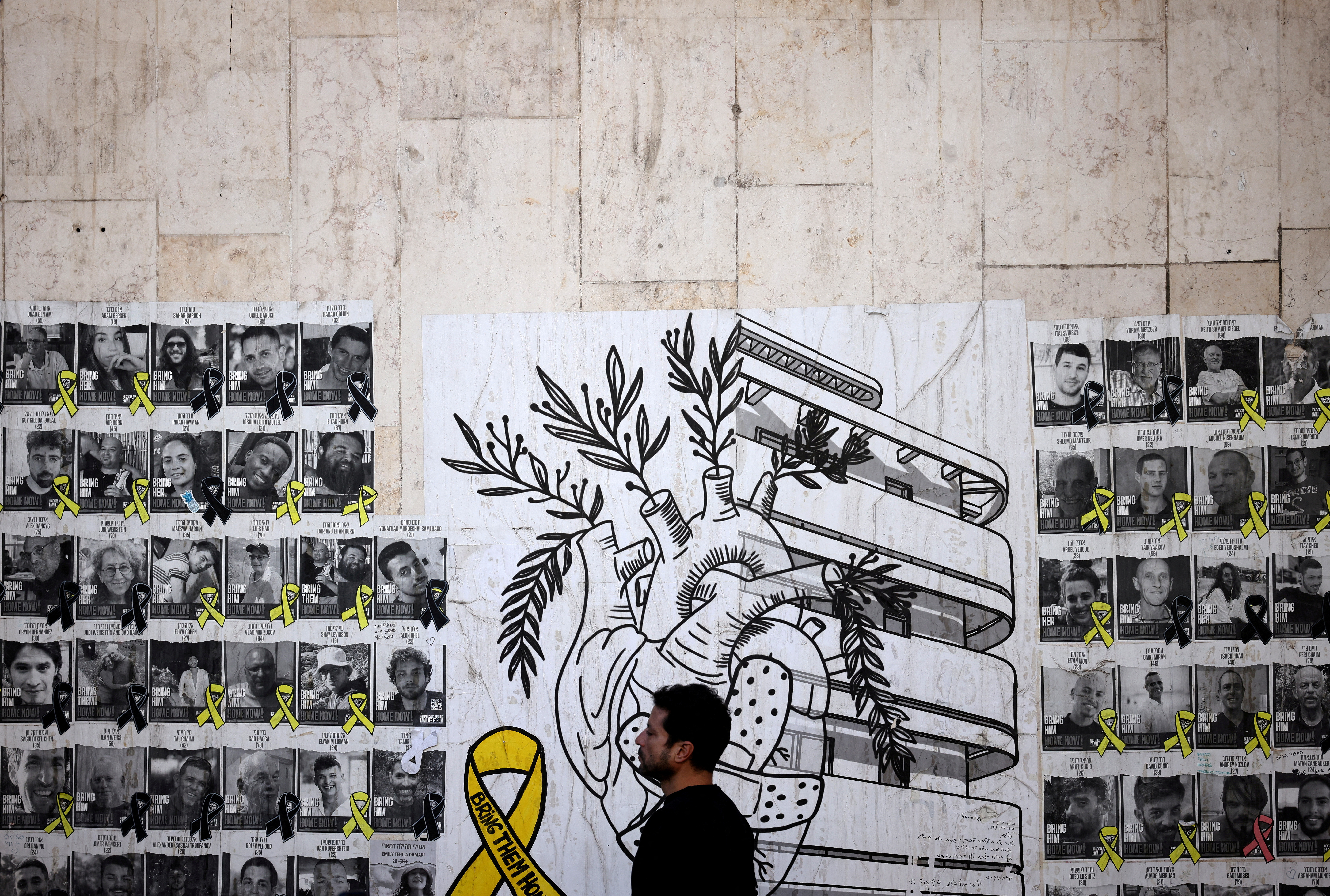 FILE PHOTO: Man walks past posters of the hostages kidnapped during the deadly October 7, 2023 attack by Hamas, in Tel Aviv