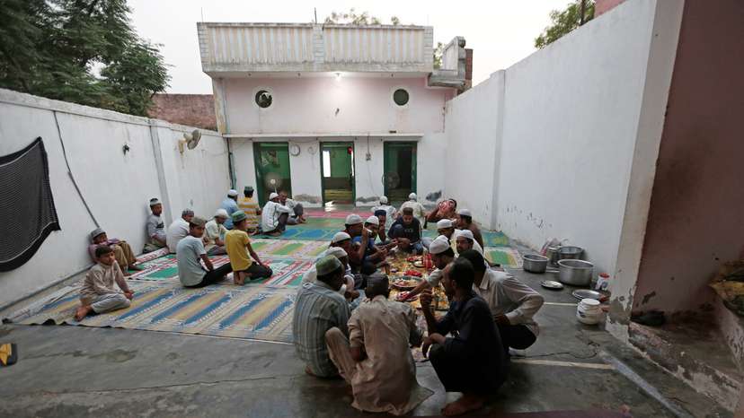 Muslims eat their Iftar (breaking of fast) meal during the holy month of Ramadan inside a madrasa that also acts as a mosque in village Nayabans