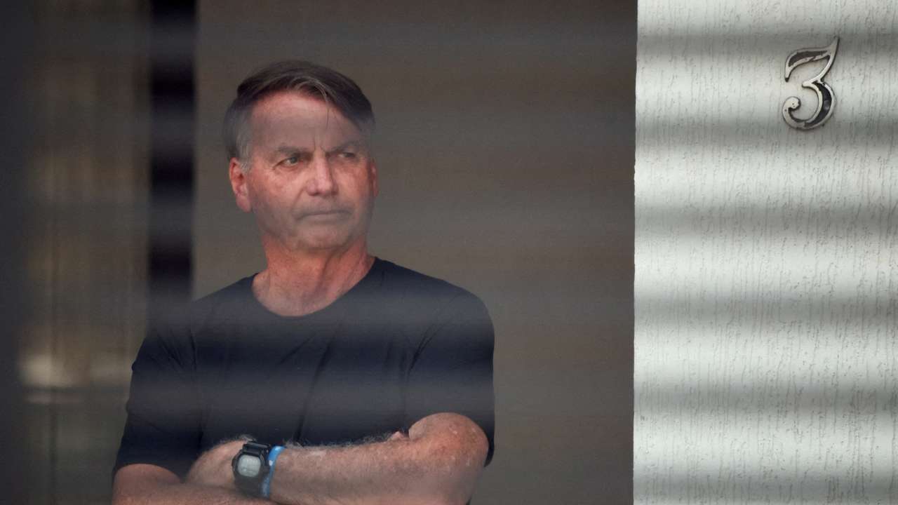 FILE PHOTO: Brazil’s former President Jair Bolsonaro stands at his home while under house arrest, in Brasilia