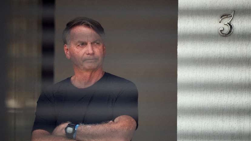 FILE PHOTO: Brazil’s former President Jair Bolsonaro stands at his home while under house arrest, in Brasilia