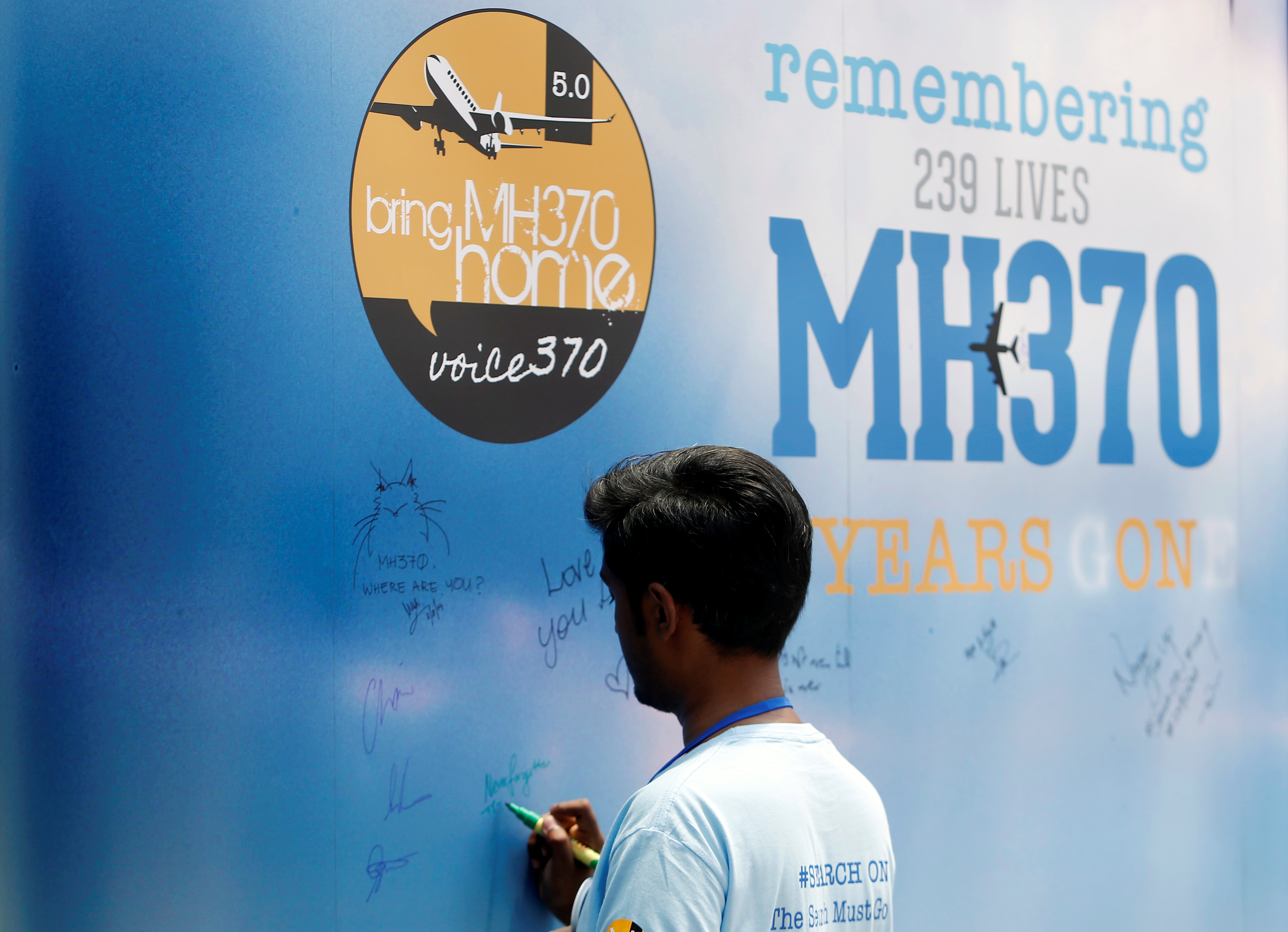 A man writes on a message board for passengers, onboard the missing Malaysia Airlines Flight MH370, during its fifth annual remembrance event in Kuala Lumpur