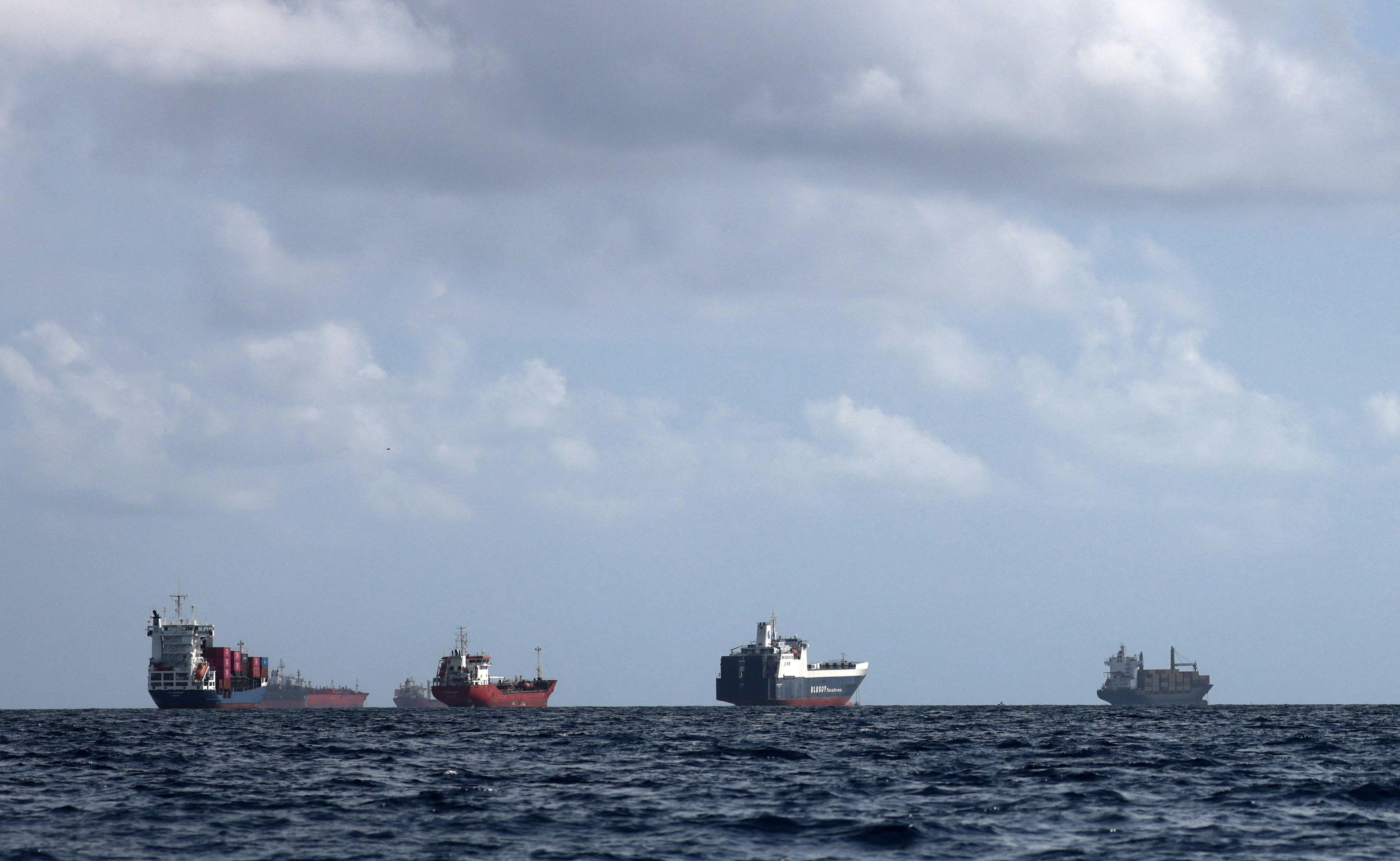 A cargo ship loaded with containers and other vessels idle offshore while waiting to enter the port of Barcelona