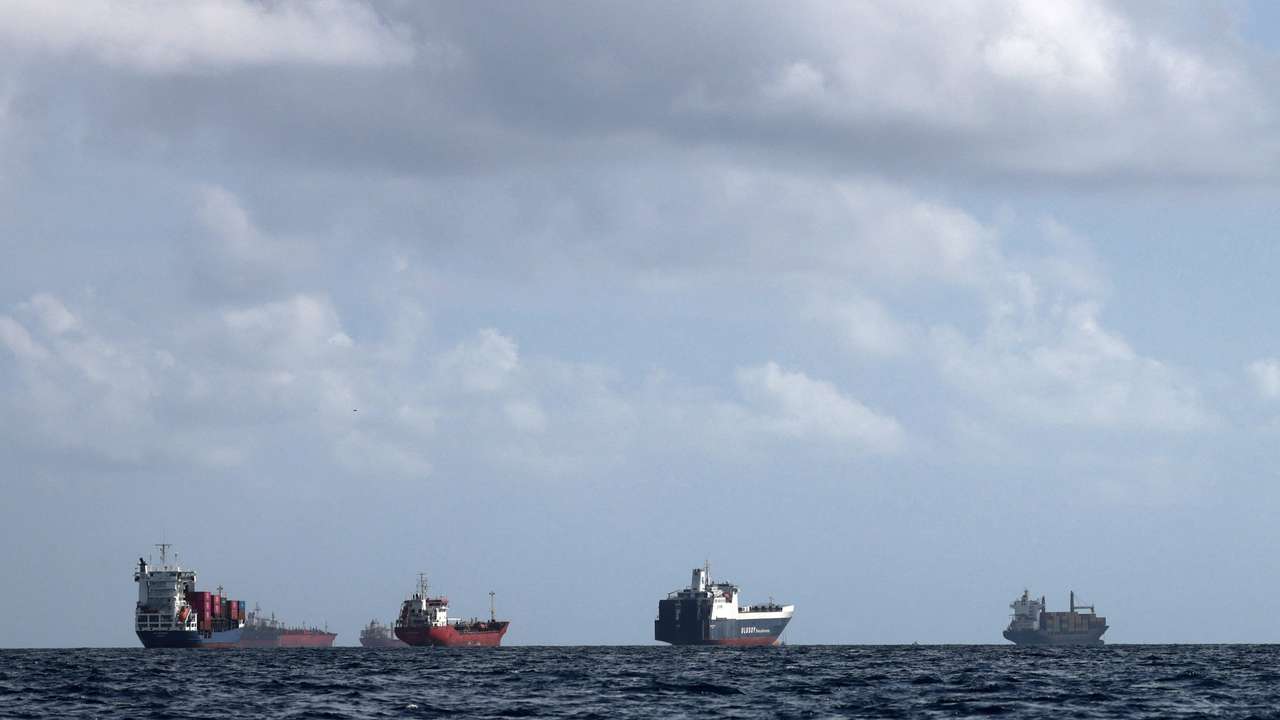 A cargo ship loaded with containers and other vessels idle offshore while waiting to enter the port of Barcelona