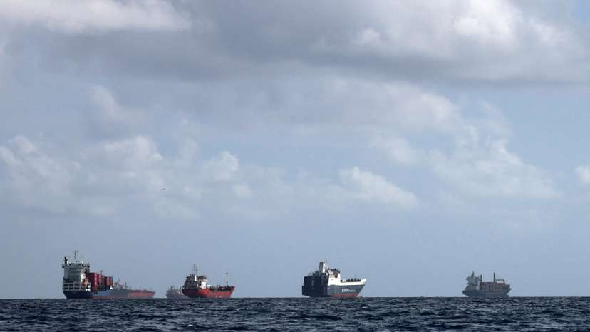 A cargo ship loaded with containers and other vessels idle offshore while waiting to enter the port of Barcelona