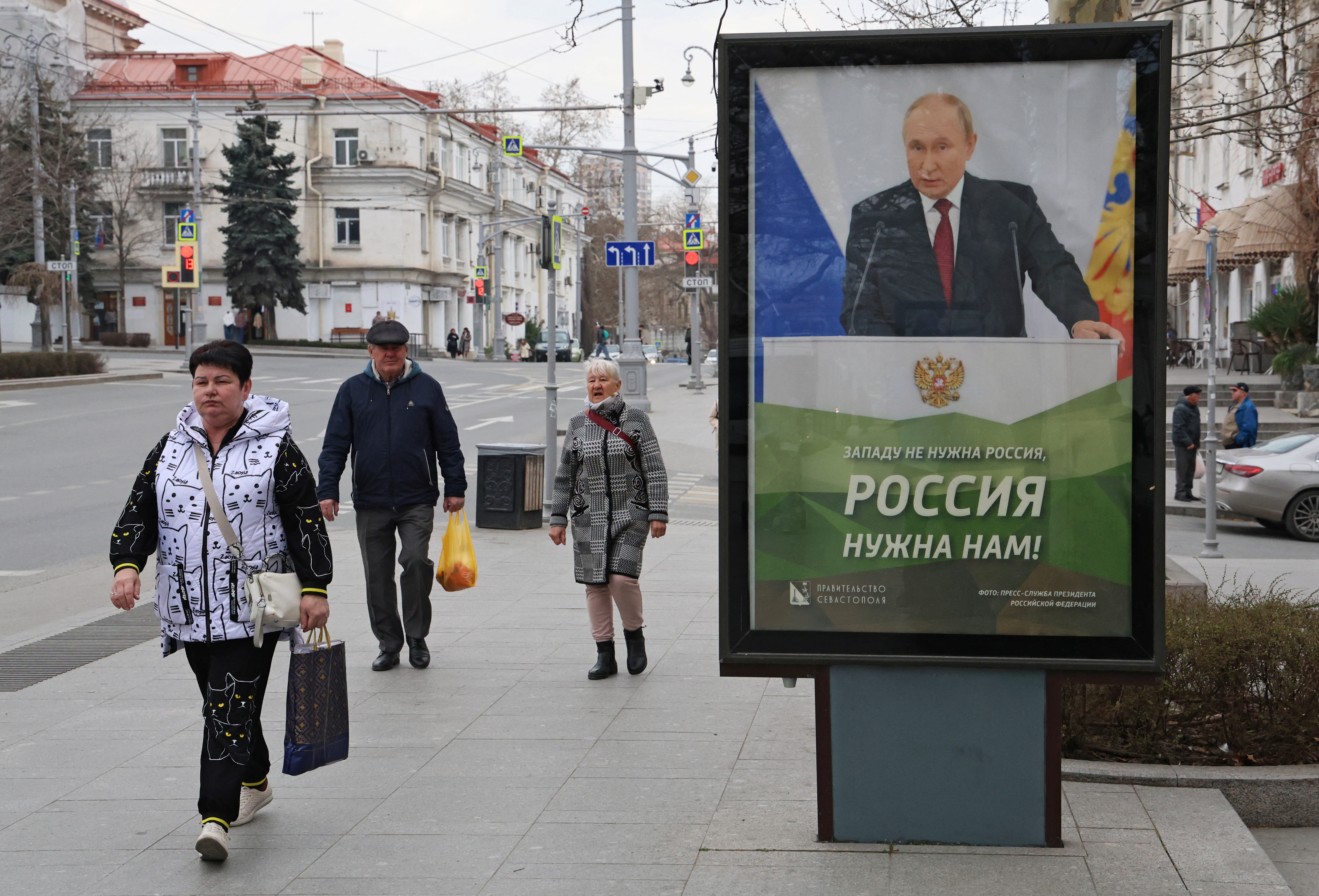 FILE PHOTO: People walk past a banner depicting Russian President Putin in Sevastopol