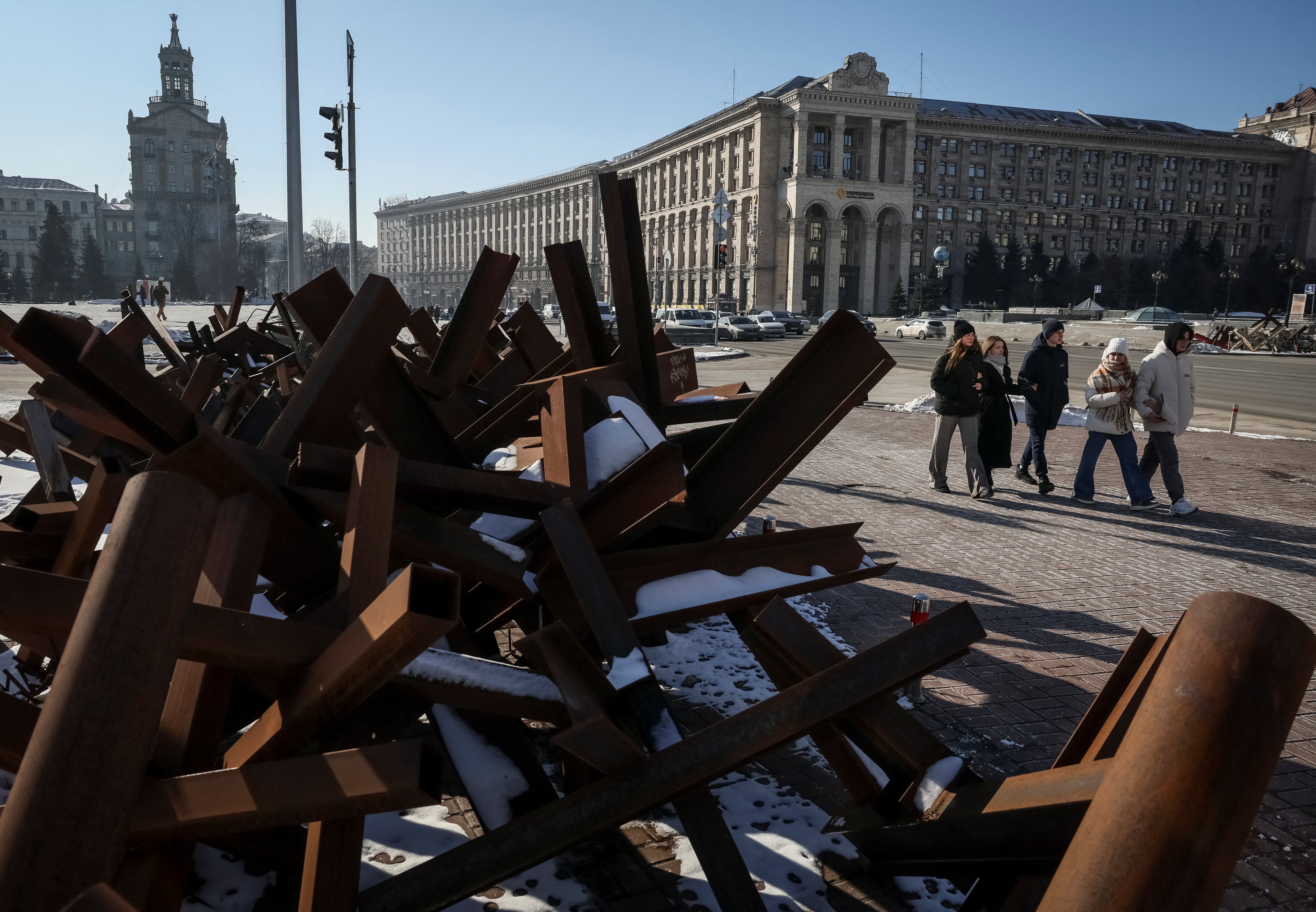 People walk down a street near anti-tank constructions in central Kyiv