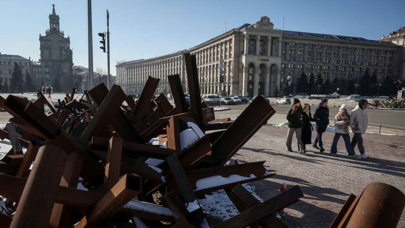 People walk down a street near anti-tank constructions in central Kyiv