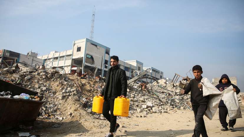 Palestinians walk past the rubble of buildings destroyed in previous Israeli strikes, ahead of a ceasefire set to take effect on Sunday, in Khan Younis