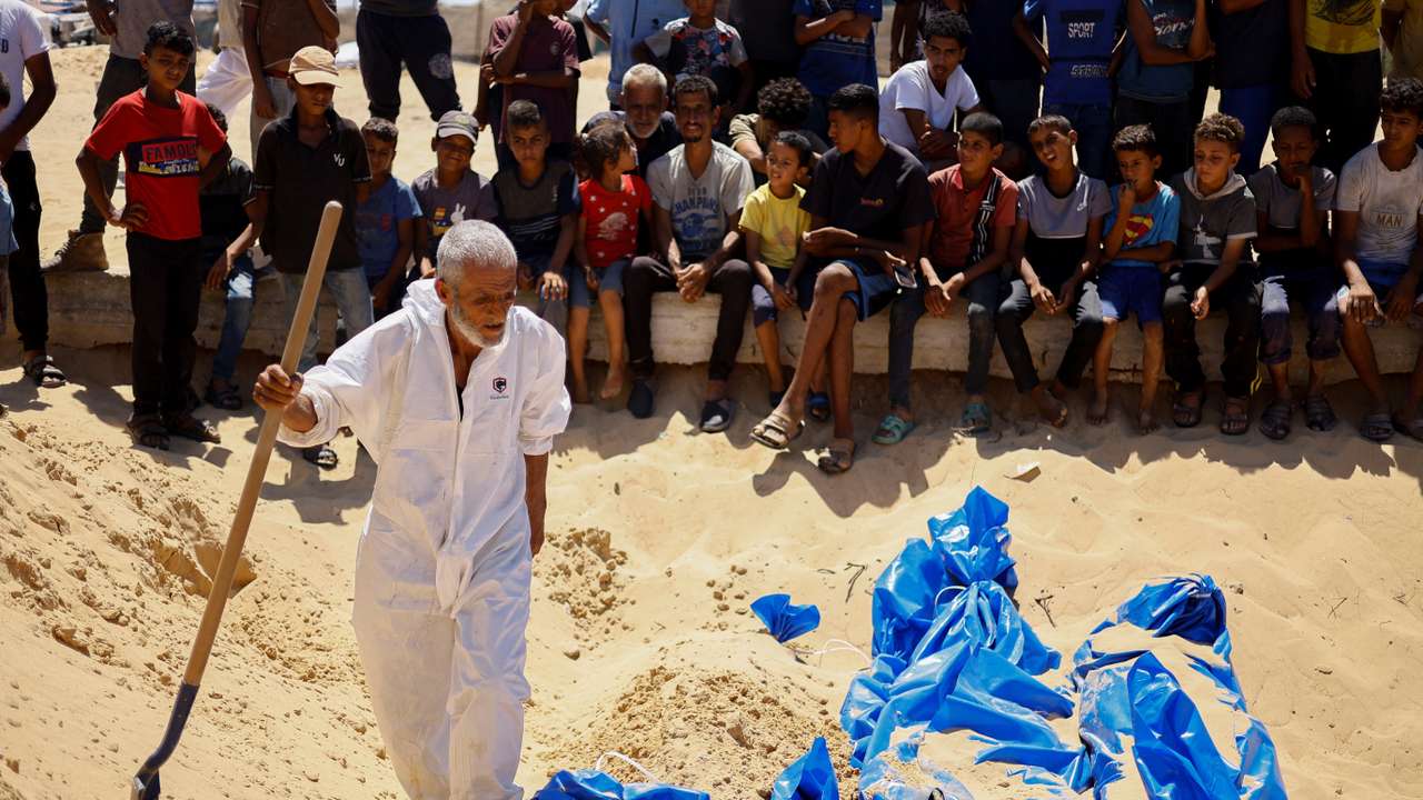 People bury the bodies of unidentified Palestinians at a mass grave after the bodies were handed over by Israel, in Khan Younis