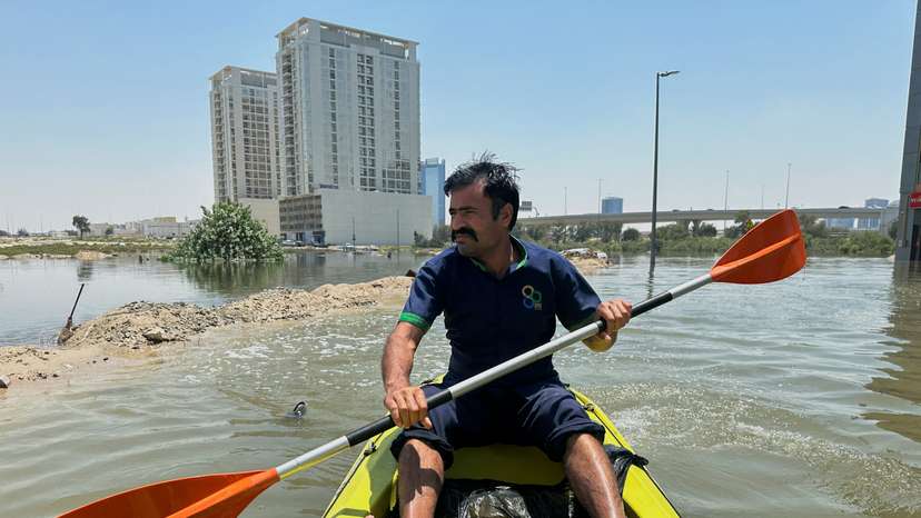 A volunteer uses a kayak during a rescue operation through a road flooded due to heavy rains in Dubai