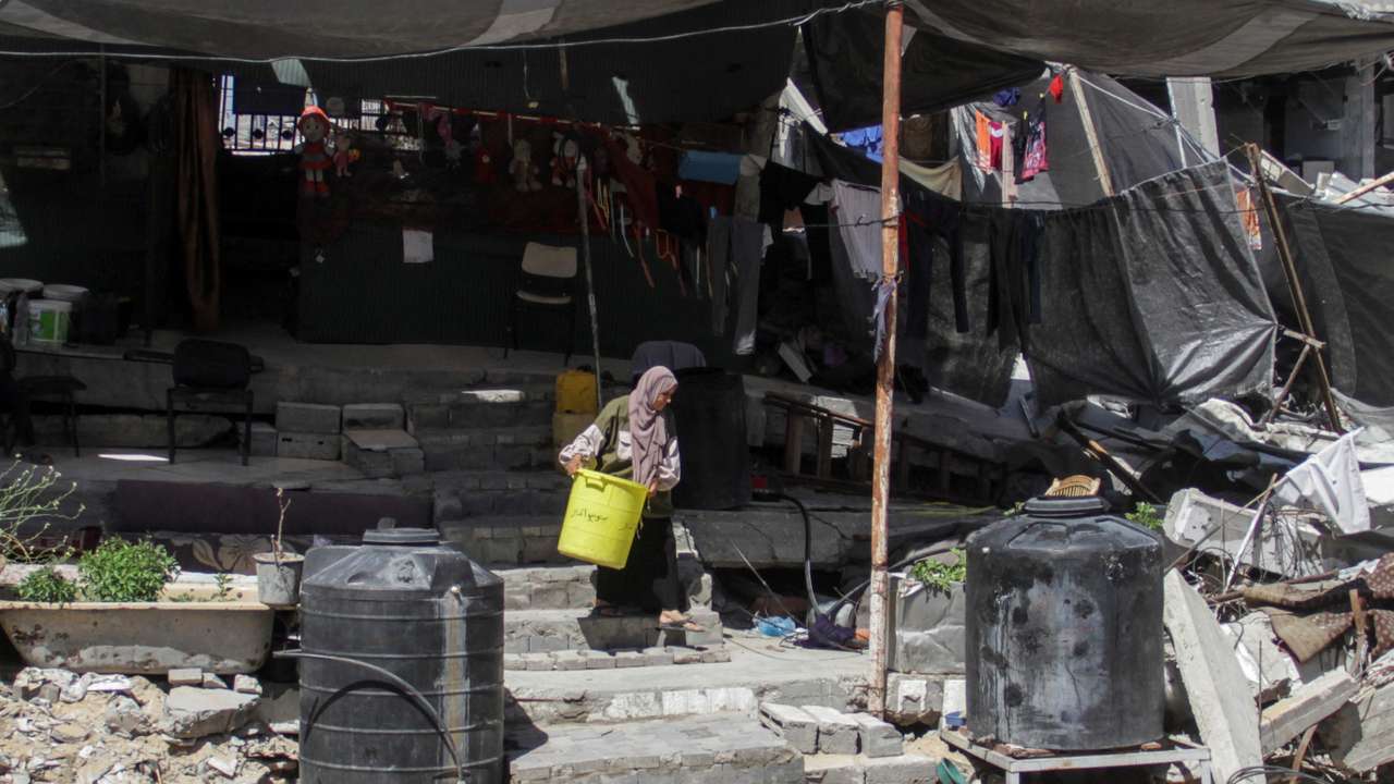 A Palestinian woman walks among the rubble of a damaged building, in Beit Lahia