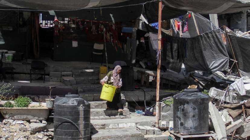 A Palestinian woman walks among the rubble of a damaged building, in Beit Lahia