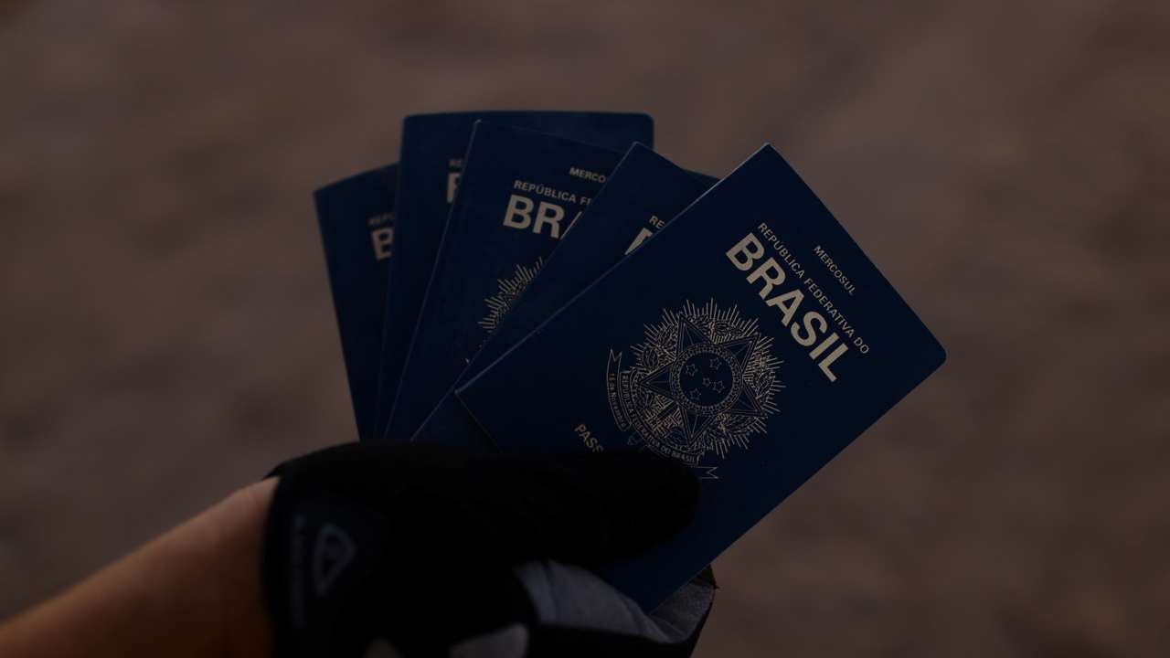 A person shows passports from Brazil that were found on the banks of the Rio Bravo River,in Ciudad Juarez