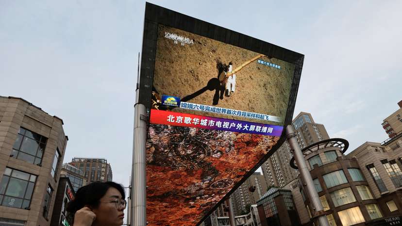Screen shows news footage of China's Chang'e-6 lunar probe collecting sample from the far side of the moon, in Beijing