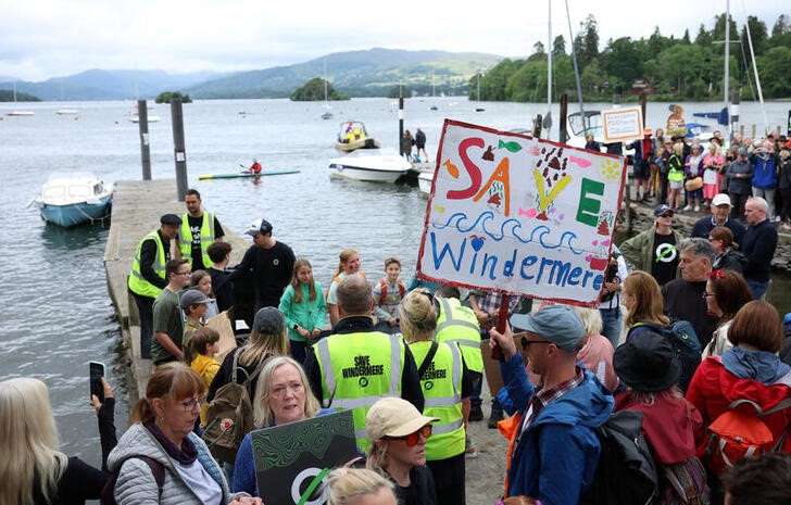 FILE PHOTO: A man holds a sign as people join a march organised by the Save Windermere campaign to protest against the dumping of sewage in England’s largest lake in Windermere