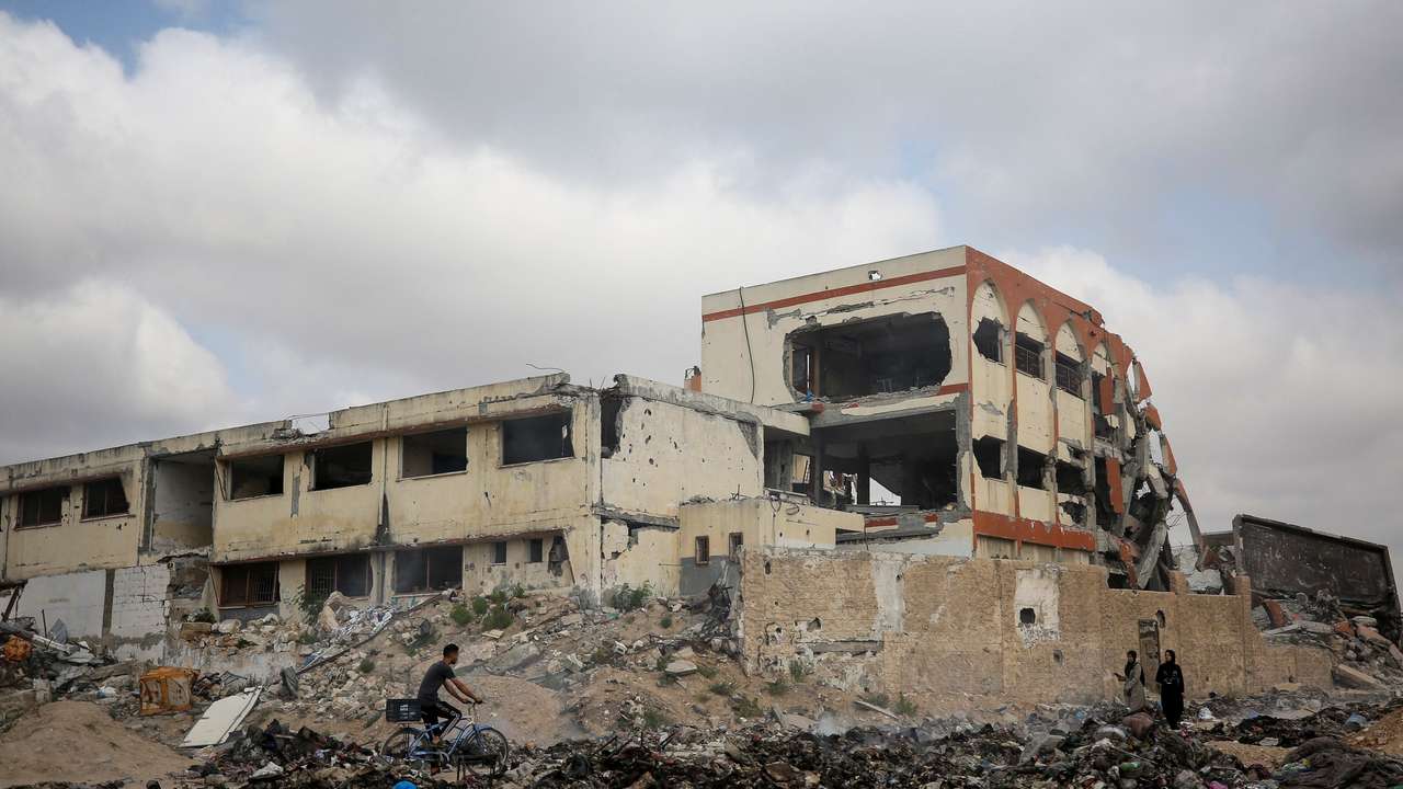 Palestinians pass by a school destroyed during Israel's military offensive, in Gaza City