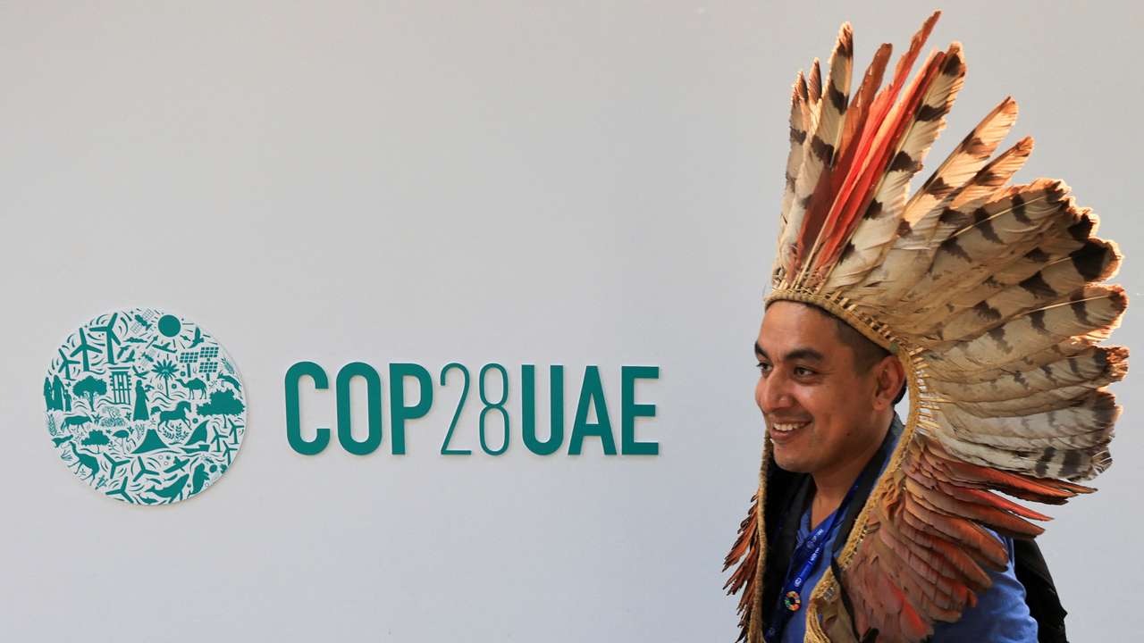 A delegate walks past a logo of the COP28 climate summit in Dubai