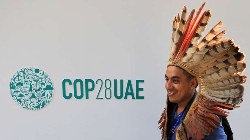 A delegate walks past a logo of the COP28 climate summit in Dubai