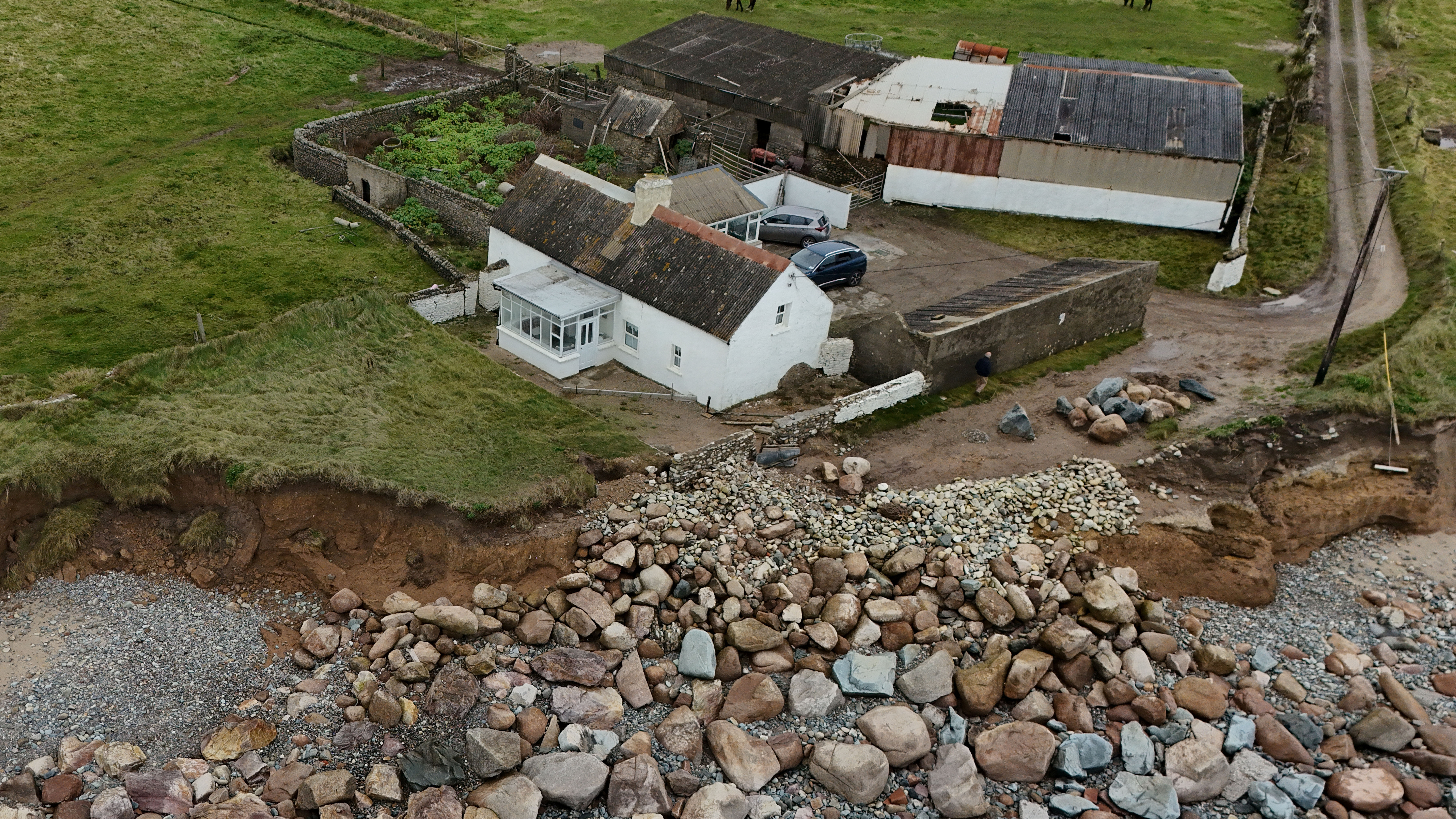 A drone view shows coastal erosion eating away at elderly couple's family home, in Ballyhealy