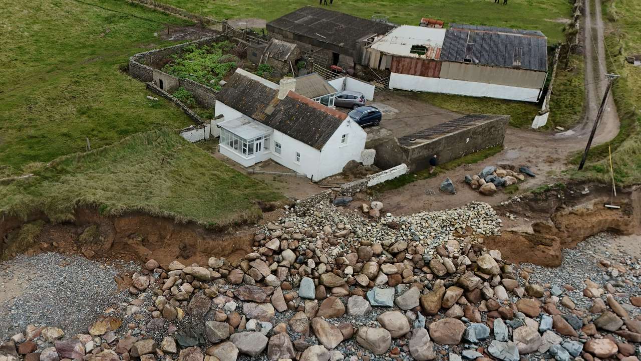 A drone view shows coastal erosion eating away at elderly couple's family home, in Ballyhealy