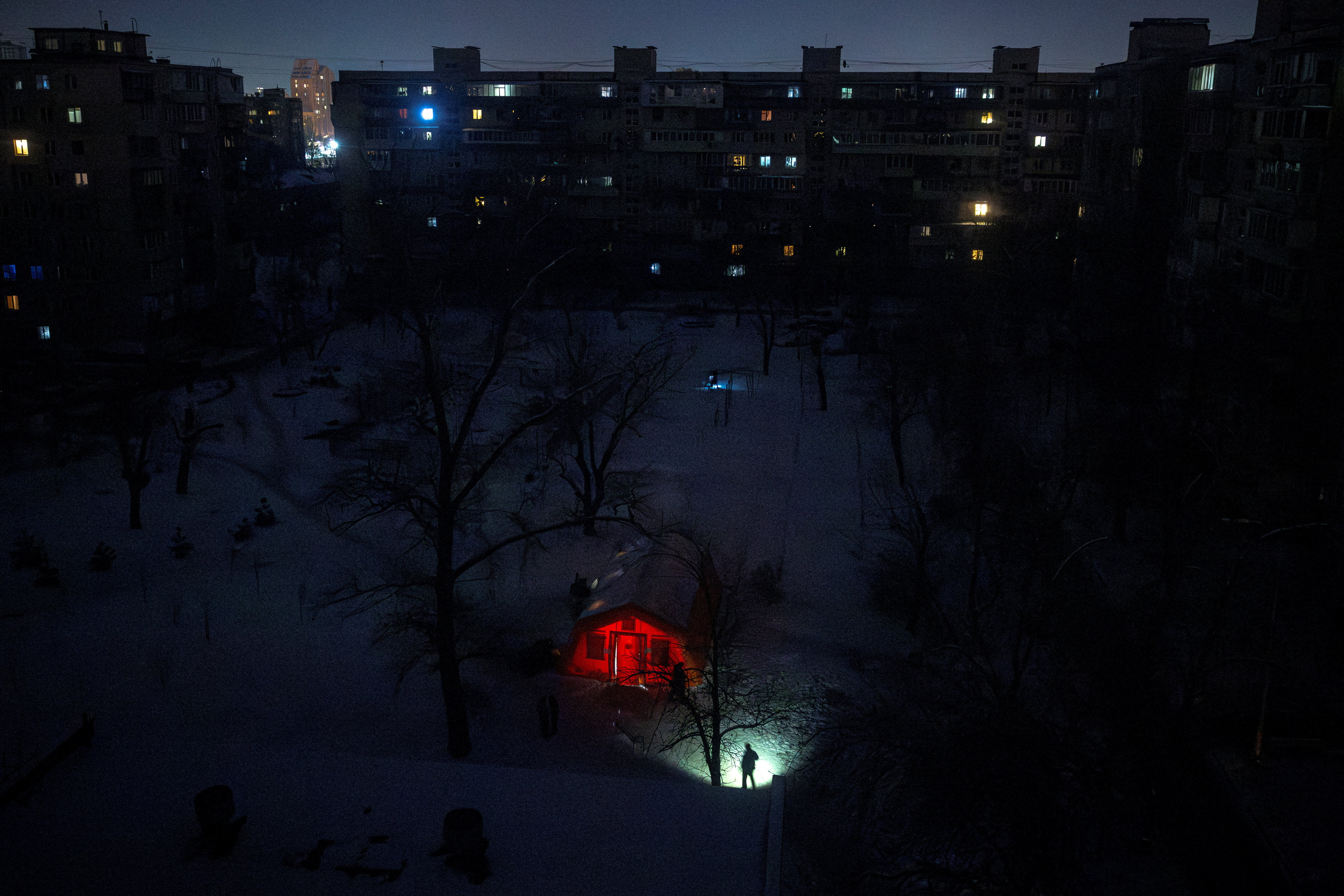 A person carrying a torch approaches a tent provided by emergency services for residents whose apartments are left without heating during sub-zero temperatures in Kyiv