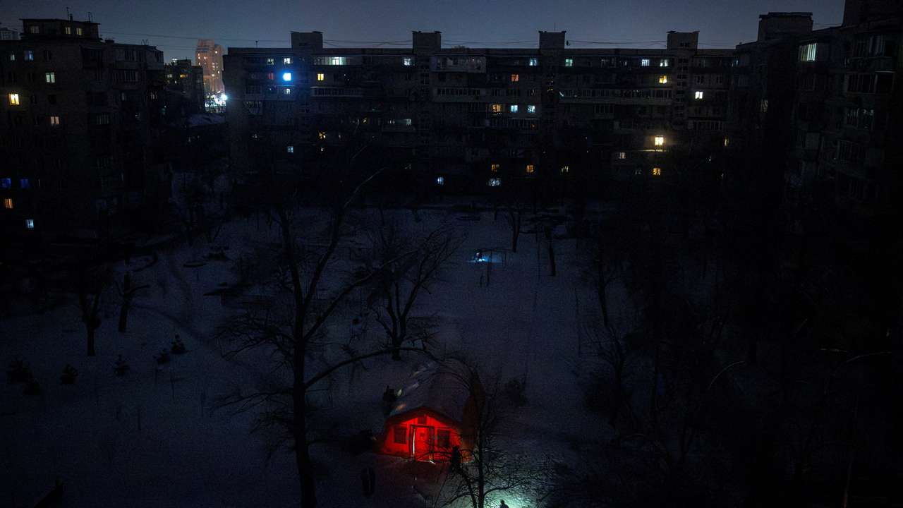 A person carrying a torch approaches a tent provided by emergency services for residents whose apartments are left without heating during sub-zero temperatures in Kyiv