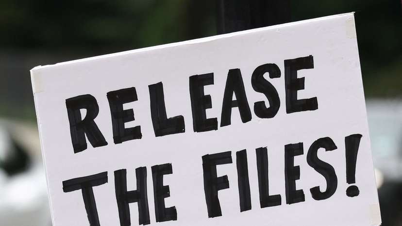 Protester holds sign before the arrival of Trump administration officials at the residence of Vice President Vance in Washington