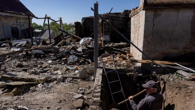A worker digs to uncover a gas pipe leading to a house that was destroyed during a Russian missile strike in Krasylivka