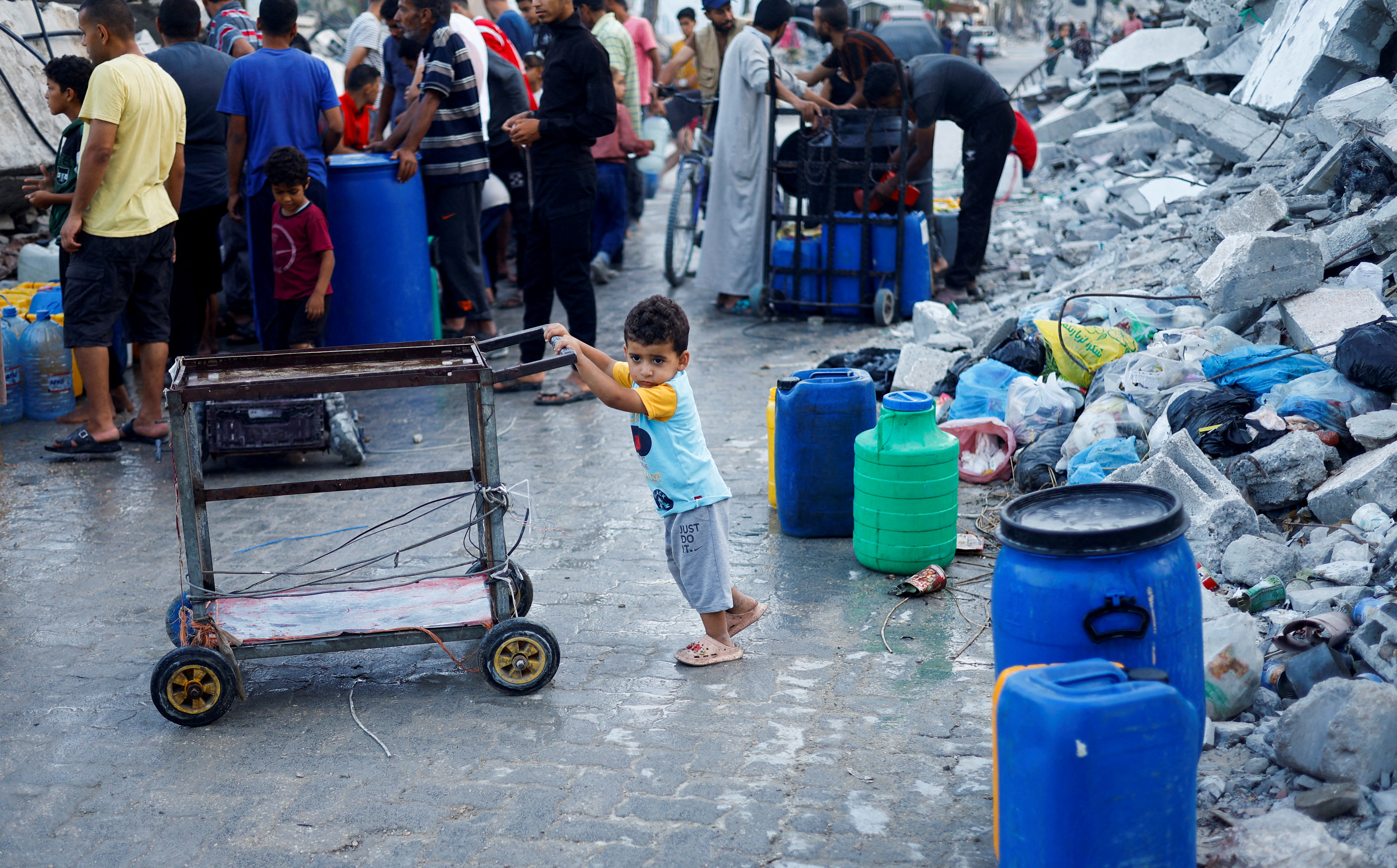 FILE PHOTO: A Palestinian child stands next to water containers, amid the ongoing conflict between Israel and Hamas, in southern Gaza City, in the Gaza Strip