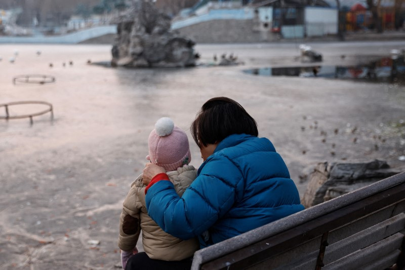 A woman and a child sit in a park in Beijing